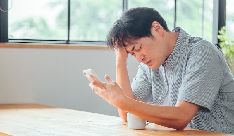 スマホを見て悩む男性